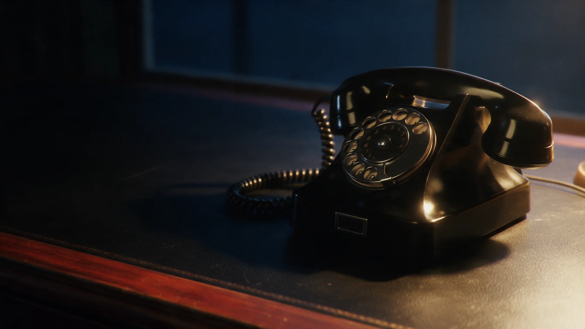 A black rotary telephone on a desk at night.